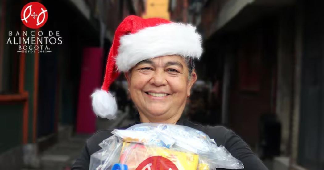 Imagen de beneficiaria con gorro de navidad y mercado por el Banco de Alimentos de Bogotá