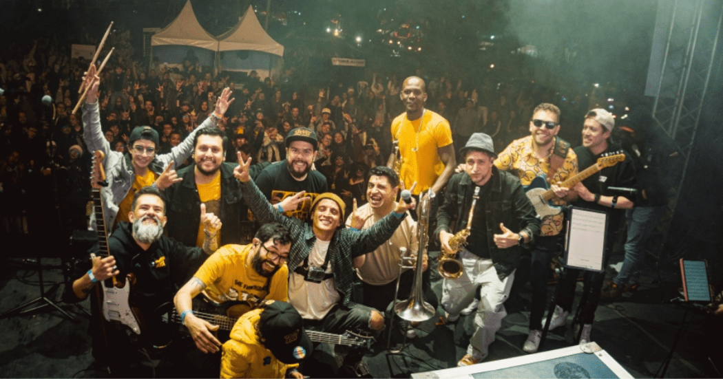 Imagen de muchos hombres en tarima de un gran evento, de fondo se ve el lugar del evento