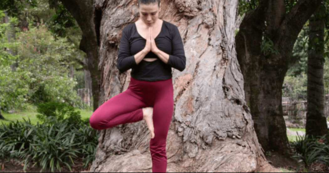 Imagen de mujer joven en posición Vrksasana, pose de equilibrio con un pie sobre una pierna