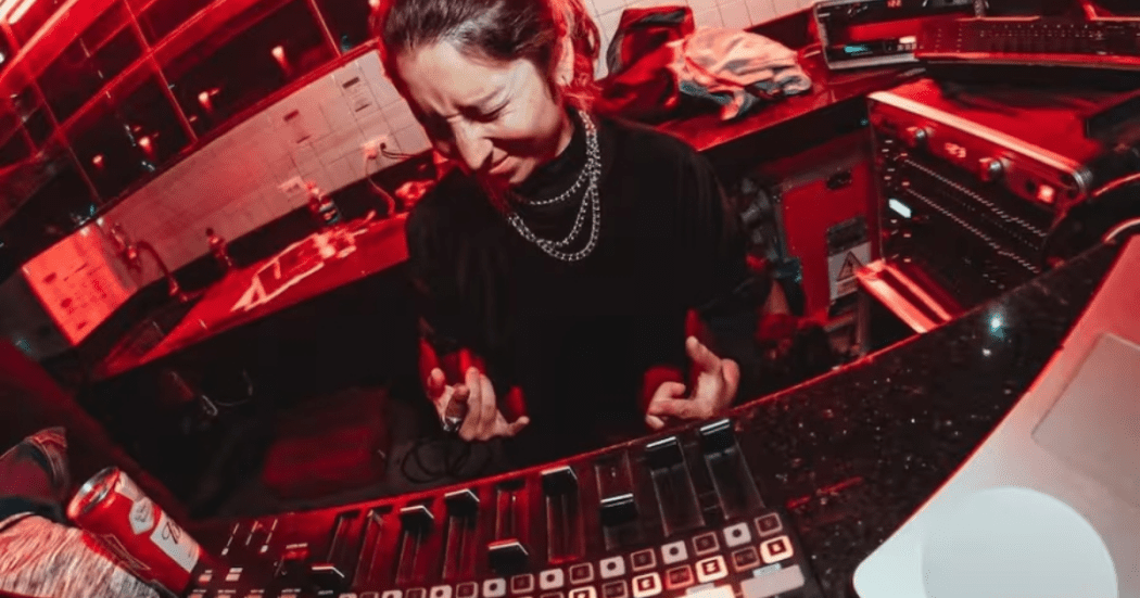 Imagen de una mujer jovén tocando música en una consola color negro