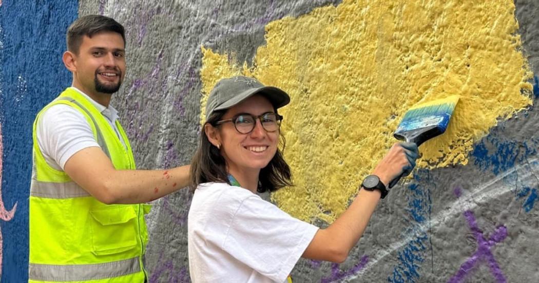 Foto de dos jóvenes realizando labores de voluntariado pintando una pared con rayones de aerosol.