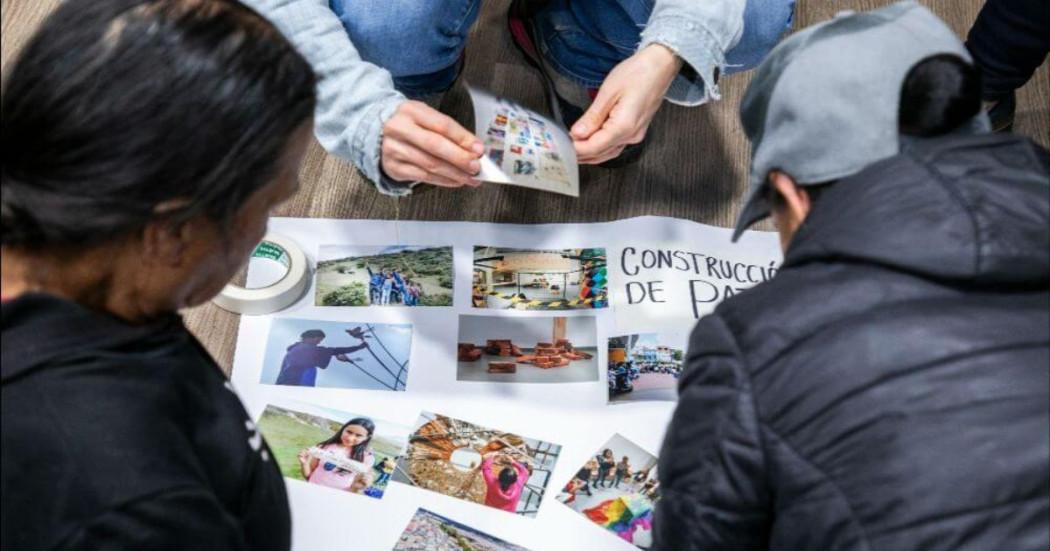 Imagen de personas pegando fotografías en una cartelera blanca