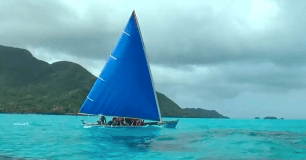 Imagen de un velero que navega en un gran mar azul, al fondo se ven algunas montañas