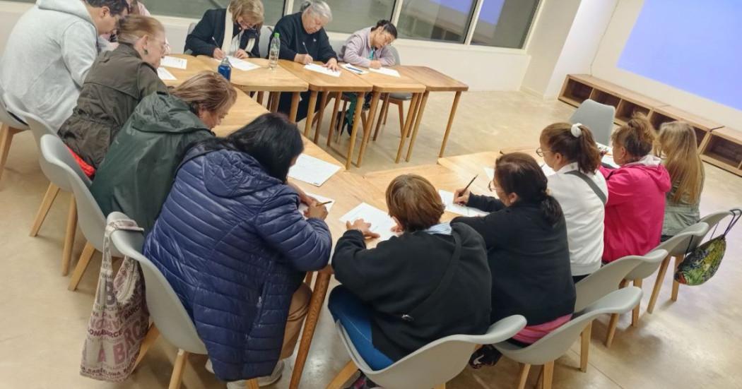 Imagen de varios adultos mayores sentados en un salón participando en la actividad