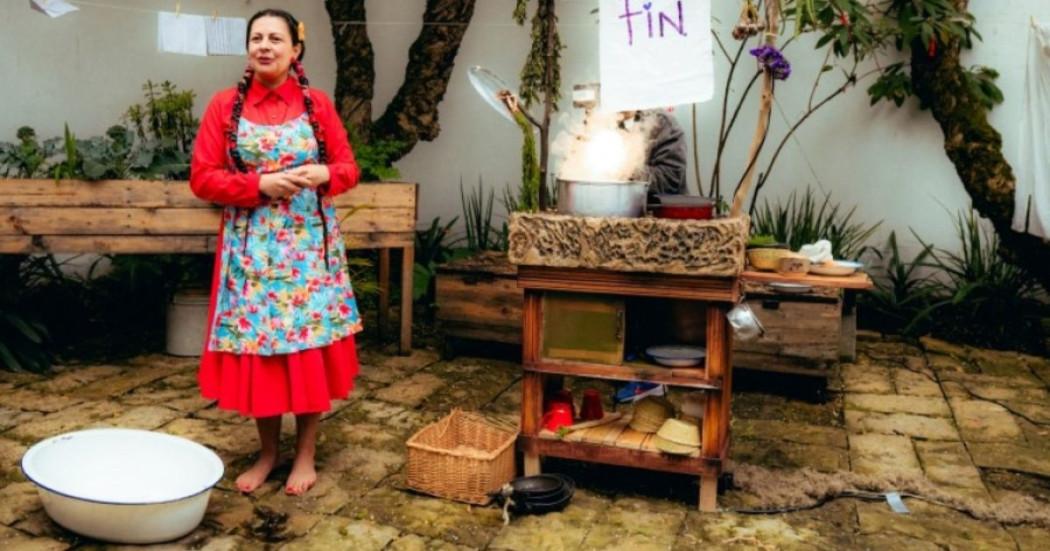 Imagen de una mujer campesina en un patio de una casa donde se ven artículos de mesa y cocina