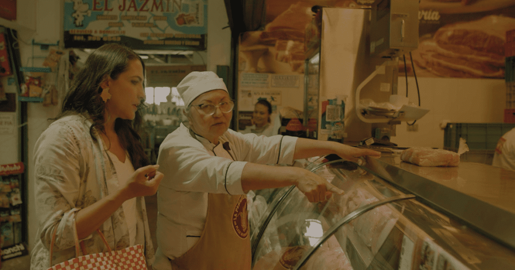 Imagen de Carolina Cuervo en una plaza de mercado donde habla con una cocinera.