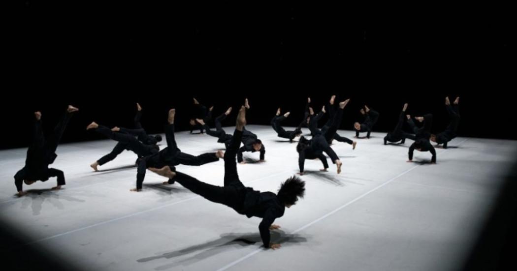 Imagen de los bailarines en la puesta en escena, ellos visten trusas negras