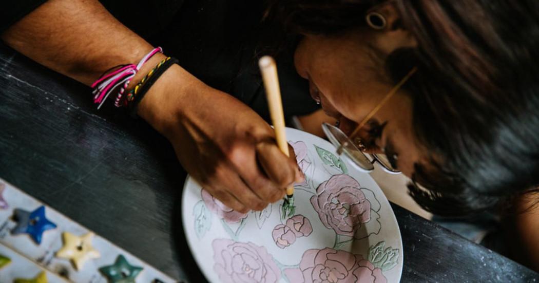 Imagen de mujer pintando sobre un plato de cerámica 