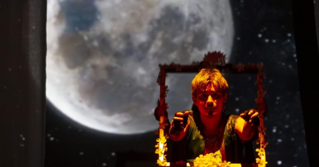 Imagen de la luna en el fondo con un hombre con marco de flores amarillas