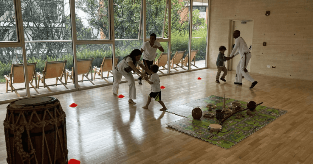 Imagen de varios niños junto a su profesor tomando una clase de capoeira.