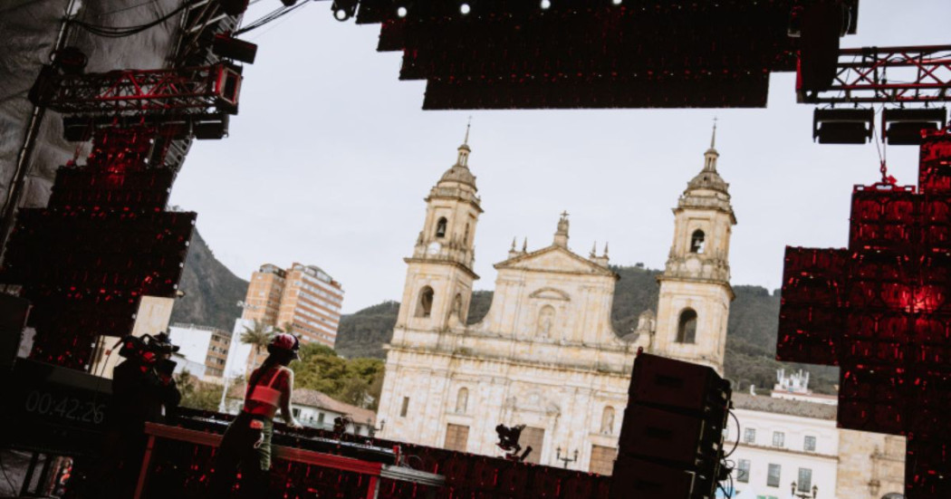 Imagen de una mujer dj tocando una consola al frente de la iglesia en la Plaza de Bolívar