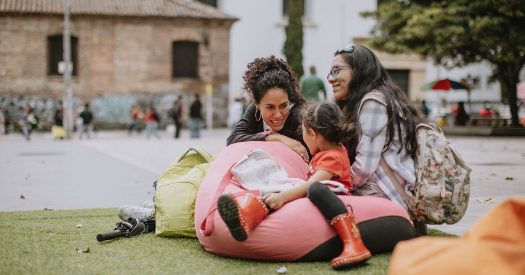 Imagen de 2 mujeres y una niña sentadas en una silla puff en actividad al aire libre en el Centro de Bogotá