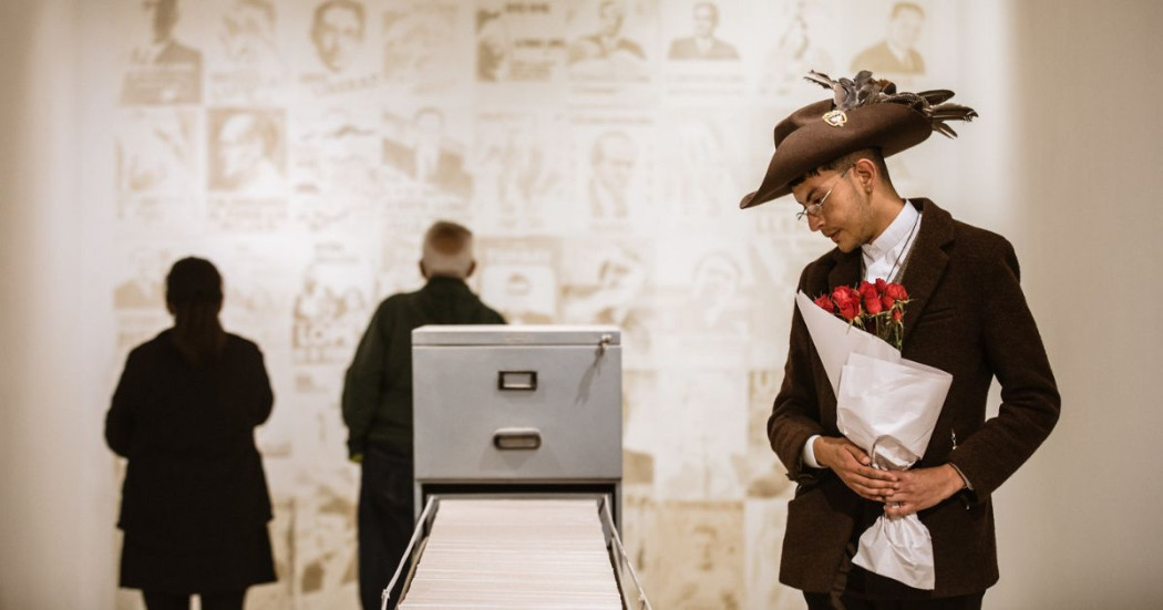 Imagen de uh hombre con sombrero y ramo de rosas mirando uno de artículos de la expo en la FUGA