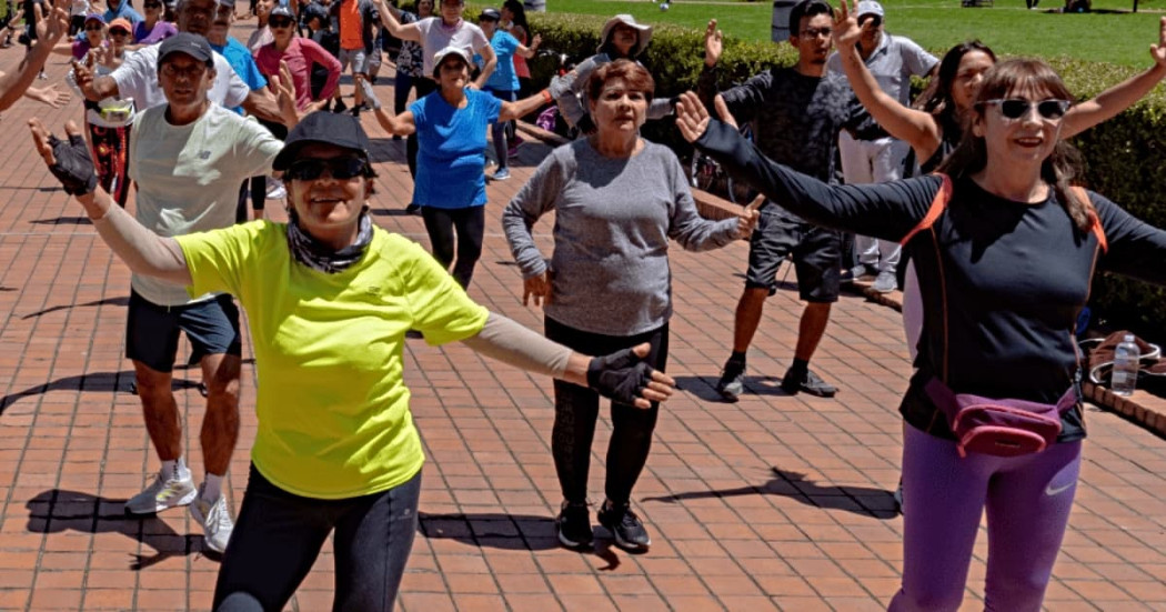Personas participan en sesión de actividad física grupal al aire libre diurna en parque de Bogotá