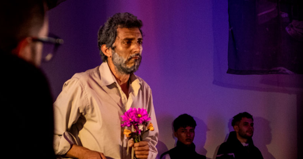 Foto de un hombre con unas flores rosadas en las manos 