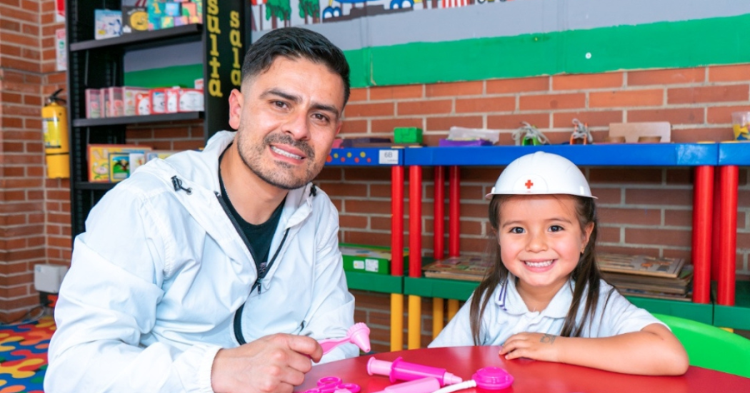 Imagen de un hombre y una niña con casco jugando sobre una mesa en las bibliotecas públicas de Bogotá