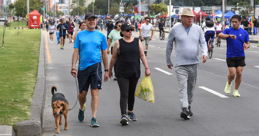 Personas caminan, trotan y se desplazan en bicicleta por una vía principal cerrada al tráfico durante jornada de Ciclovía en Bogotá
