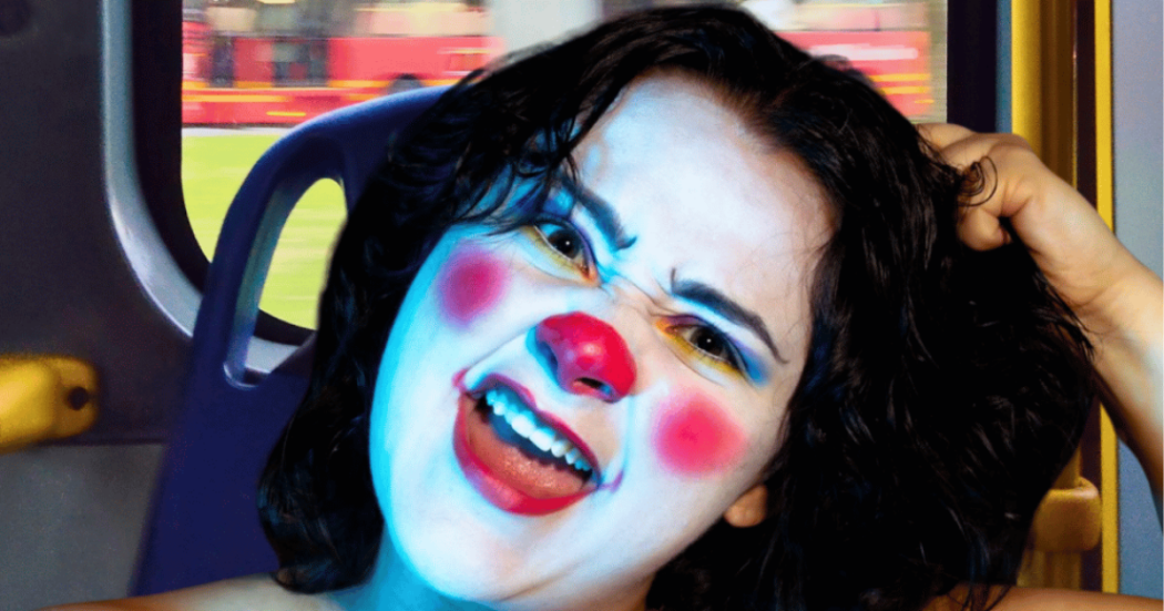 Imagen de una mujer joven que tiene su cara pintada como una payasa.
