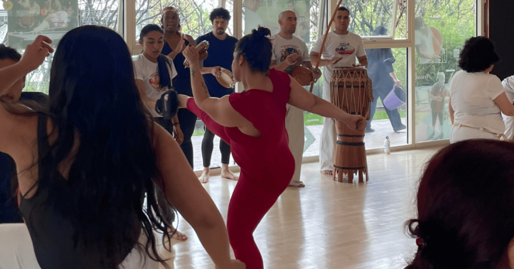 Imagen de varias mujeres tomando clase de capoeira en Cefe Chapinero, al fondo se ve un conjunto con instrumentos musicales.