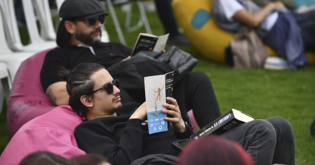 Imagen de dos hombres leyendo un libro sobre un sillón en picnic literario 2025