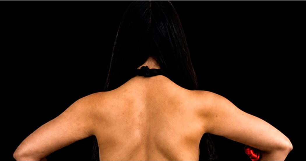 Imagen de una mujer de espaldas donde se aprecia su cabello y brazos.