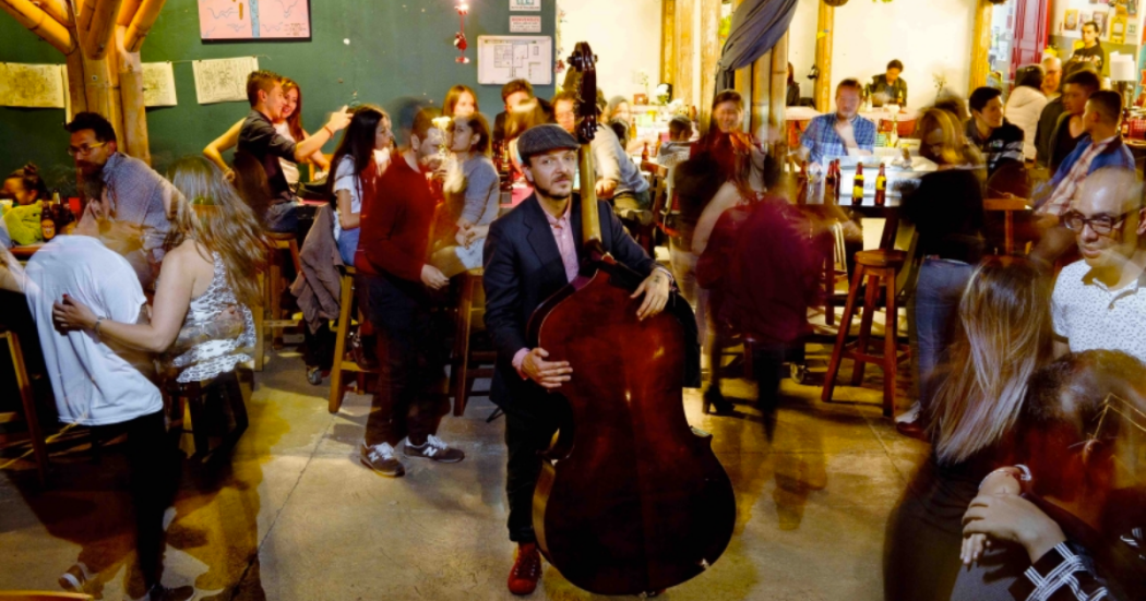 Imagen de varias personas en un salón de baile y un hombre tocando violín.