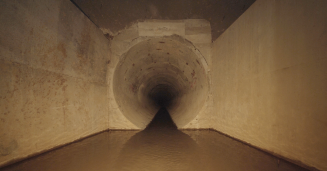 Imagen sobre un espacio de la exposición Katabasis donde se aprecia una pared en concreto beige.