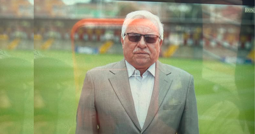 Imagen de un hombre mayor que usa gafas oscuras, al fondo se ve una cancha de fútbol.