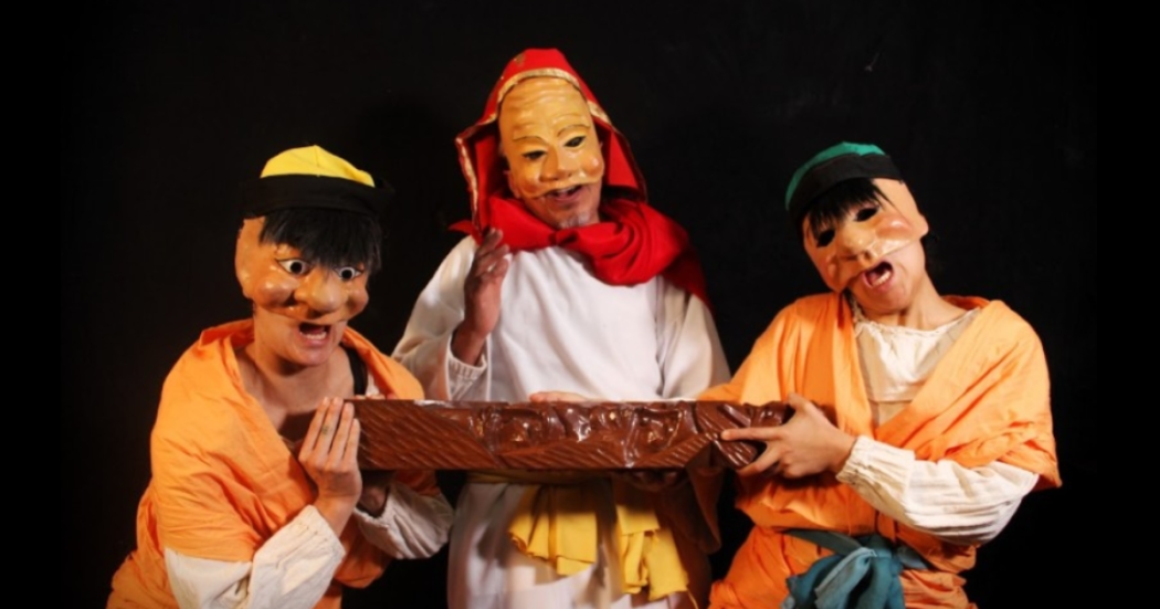 Imagen de los tres protagonistas de la obra, un hombre mayor y dos jovenes que usan máscaras.