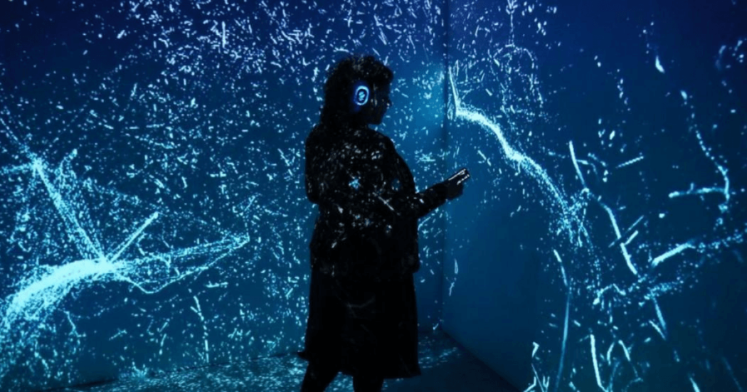 Imagen de una mujer con audifonos en un espacio oscuro con luces en un evento en Bogotá.