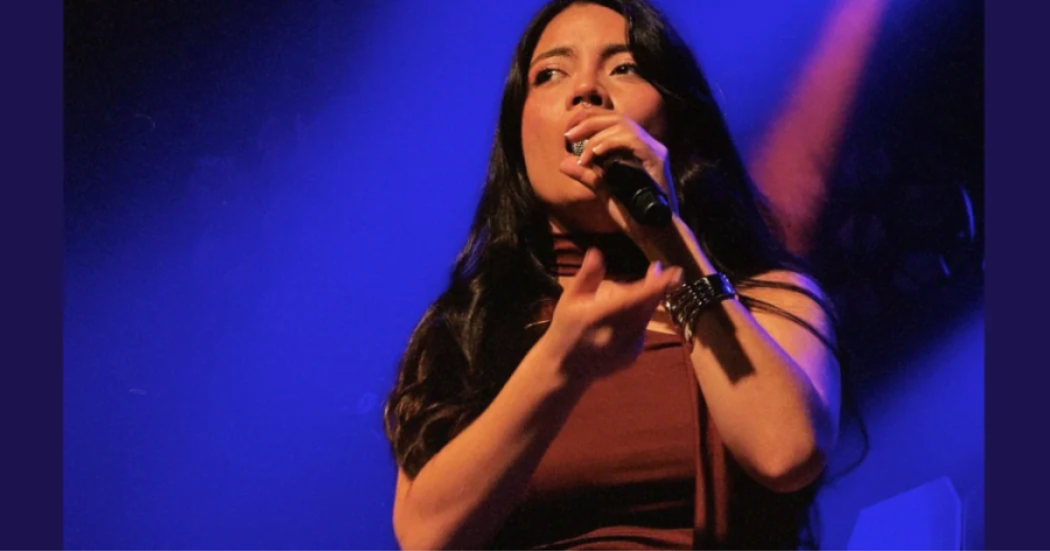 Imagen de una mujer joven que canta con un micrófono en su mano.