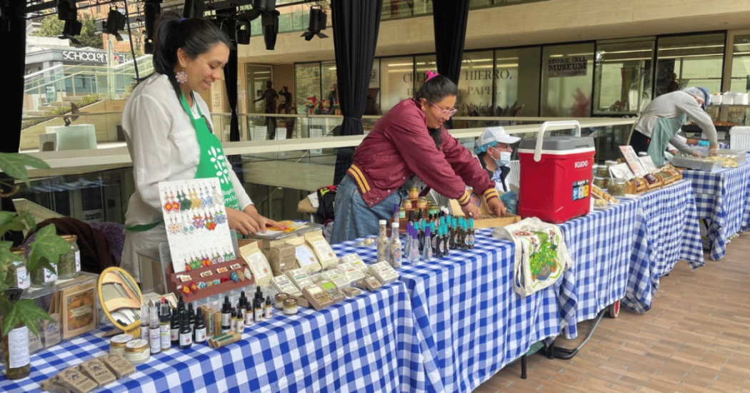 Imagen de varias personas que ofrecen en sus stand los productos de mercado campesino.