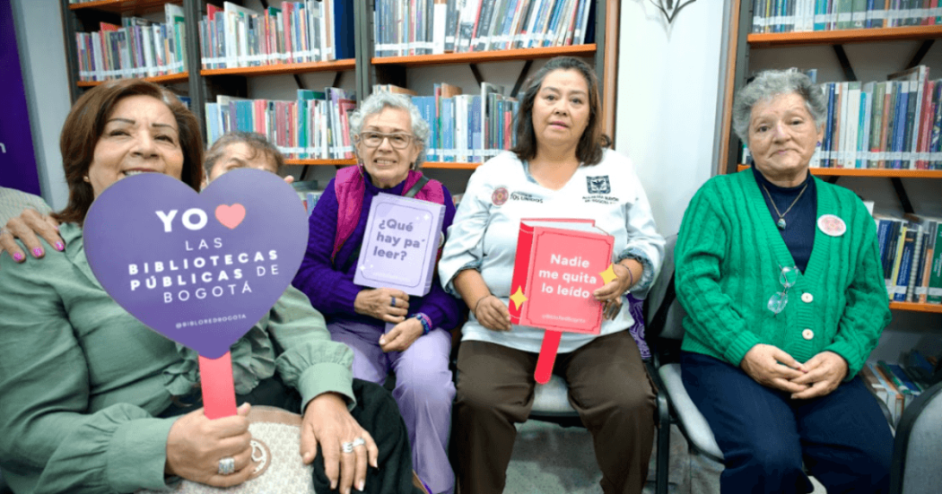 Imagen de adultas mayores en las bibliotecas públicas de Bogotá con cartel en letras Yo amo las bibliotecas...