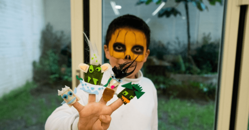 Imagen de niño con antifaz y títeres en la mano