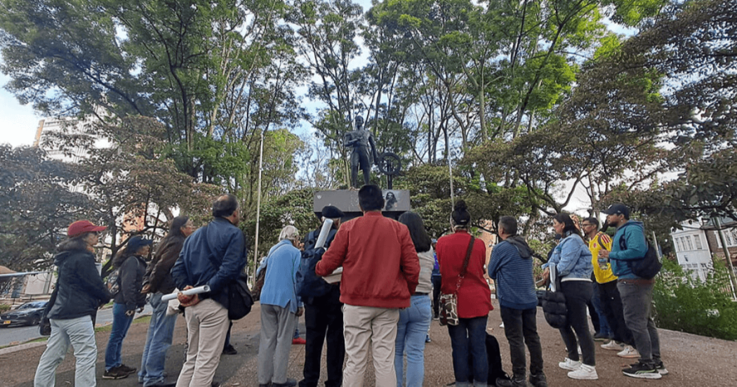 Imagen de personas alrededor de una estatua en espacio público