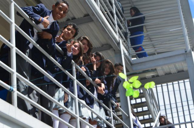 Niños se asoman desde el balcón de un colegio.