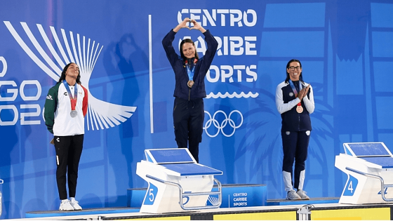 Deportistas reciben medallas durante ceremonia de premiación de los Juegos Centroamericanos y del Caribe Santo Domingo 2026, sobre el podio frente al panel oficial del evento.