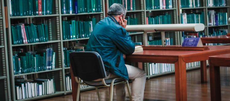 Hombre leyendo un una biblioteca