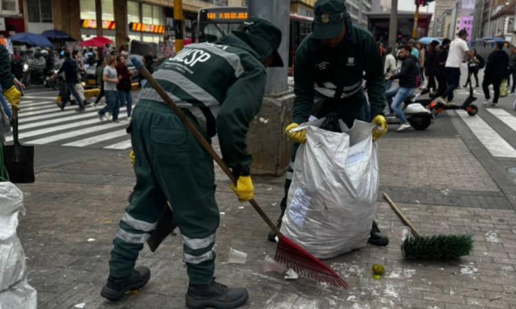 Foto que muestra dos trabajadores de la UAESP levantando basura de las calles