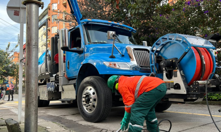 Imagen de un técnico de la Empresa de Acueducto realizando mantenimiento en la tubería de una calle, al fondo se ve un carrotanque