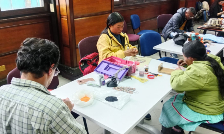 Imagen de varios artesanos trabajando sentados en una mesa