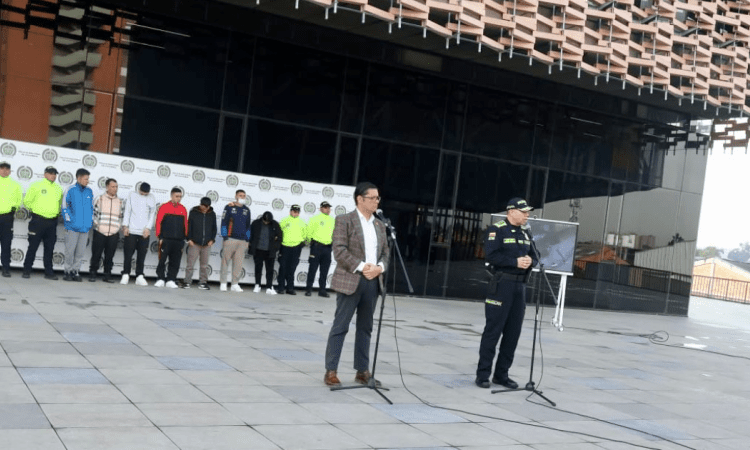 Imagen de la rueda de prensa en la que se ve al secretario de seguridad y detrás de él a los capturados