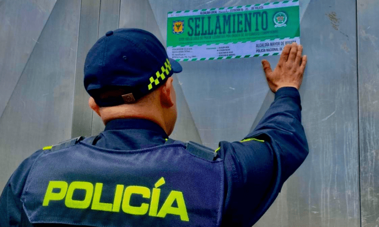Imagen de un Policía poniendo un letrero de sellamiento