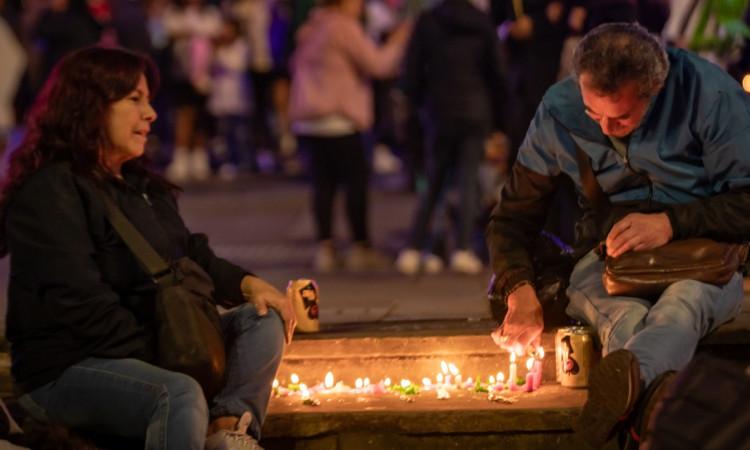 Foto que muestra dos personas sentadas en el piso prendiendo velas