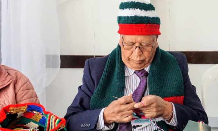 Imagen de una persona mayor tejiendo una bufanda navideña