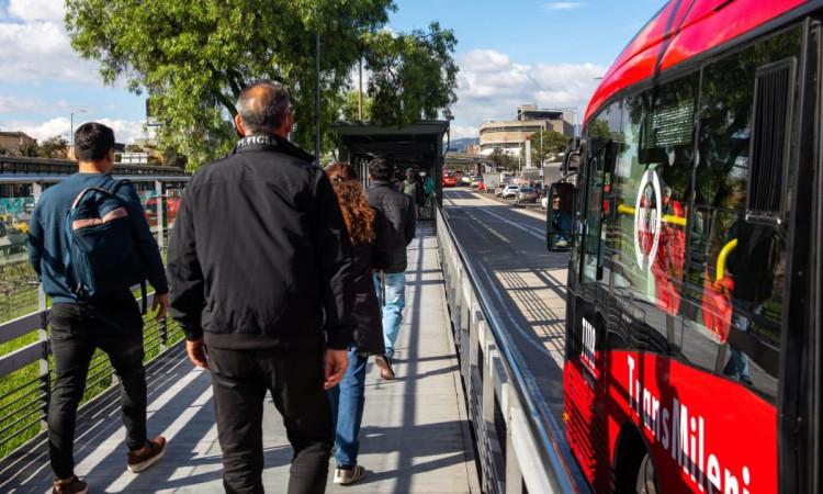 Foto de personas junto a un bus de TransMilenio