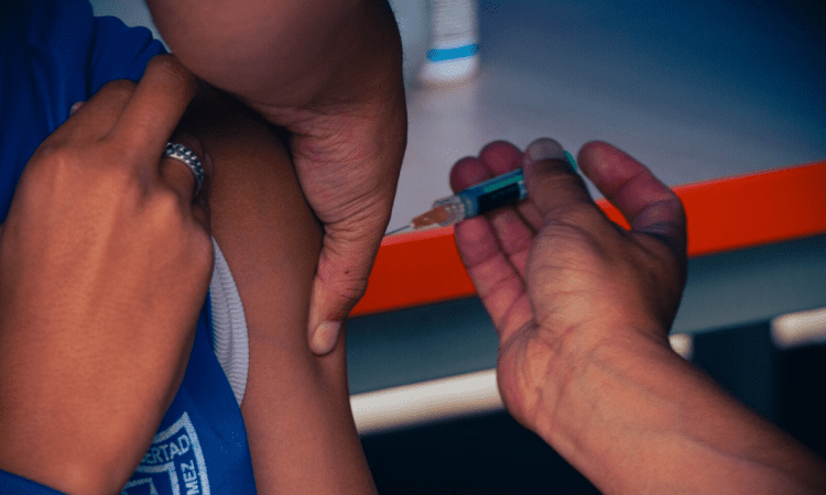 Foto de una mano aplicando una inyección a un niño 