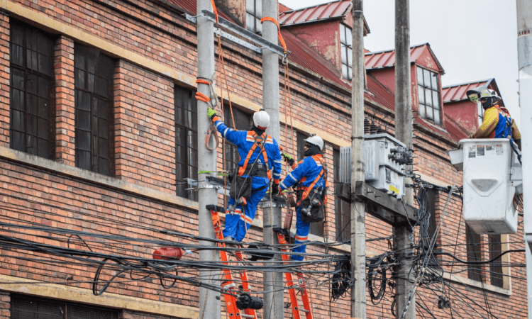 Imagen de técnicos de Enel colgados en postes de luz
