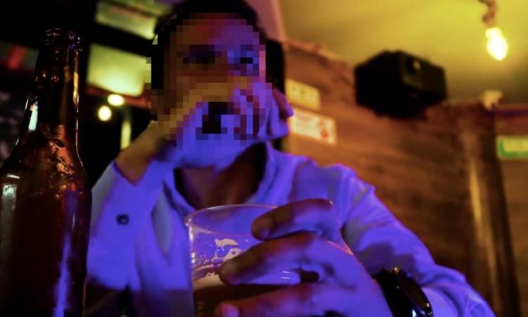 Foto de un hombre en un establecimiento nocturno consumiendo una bebida.