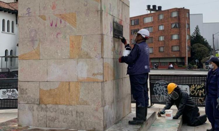 Foto que muestra un monumento de la ciudad y tres personas limpiandolo